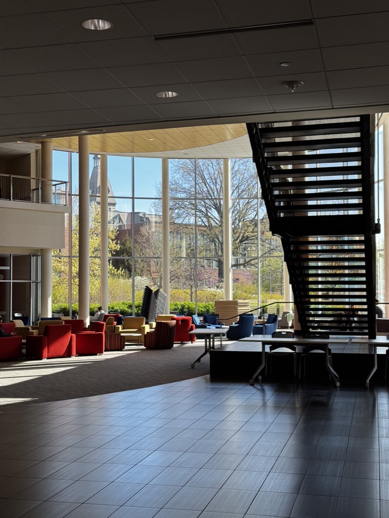 Hamline's Anderson Center lobby with colorful lounge seating, a sweeping staircase, and floor-to-ceiling windows looking onto campus