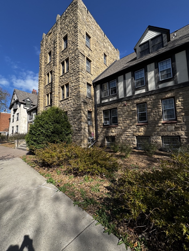 A stone tower and Tudor-style residence hall on Hamline's campus under a clear blue sky