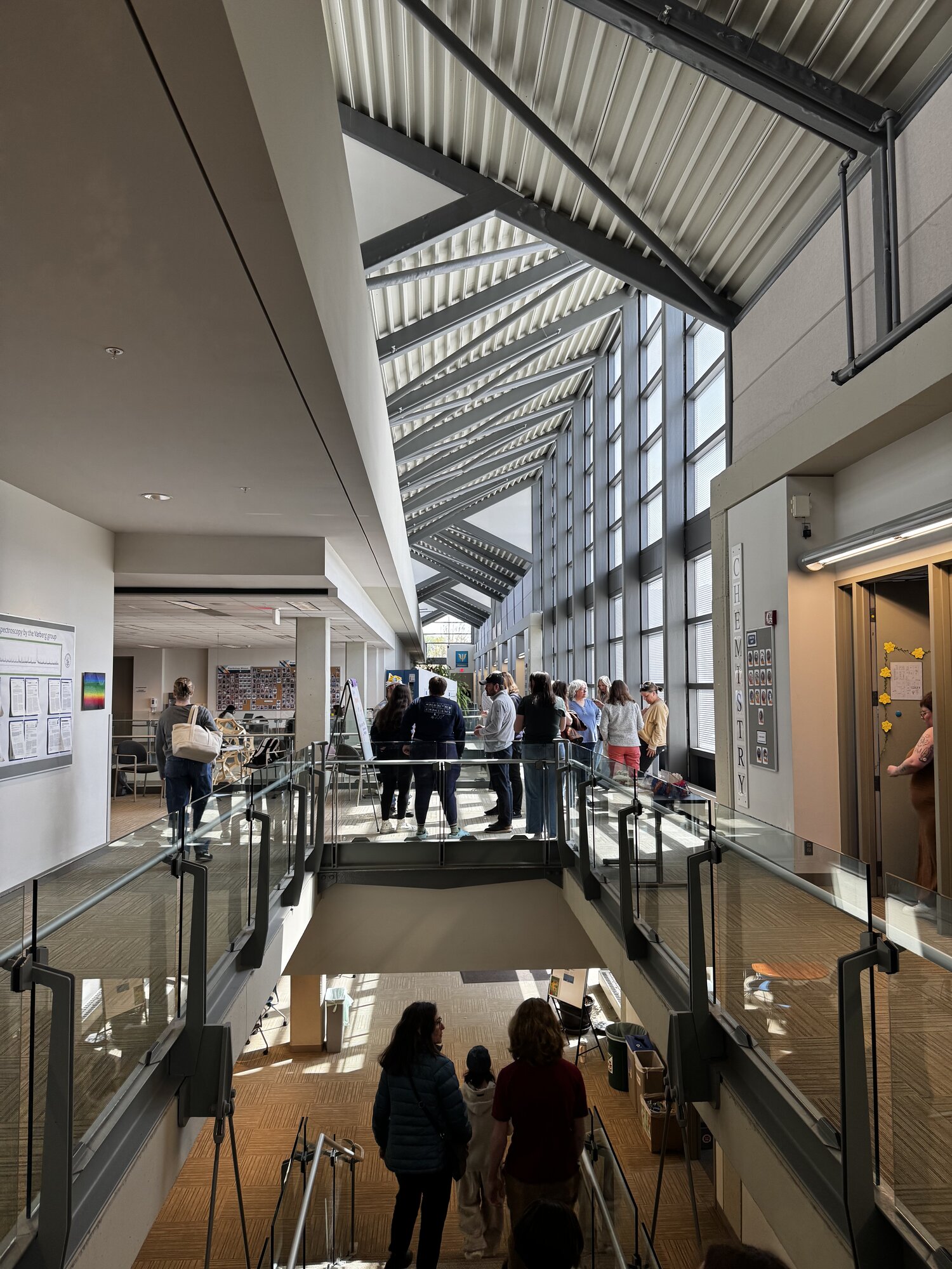 Students gathered on the bridge inside Macalester's Olin-Rice Science Center under a soaring skylight