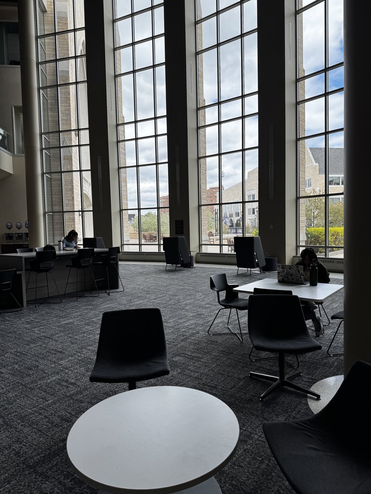 Students working at high tables beside floor-to-ceiling windows in a sunlit St. Thomas study lounge