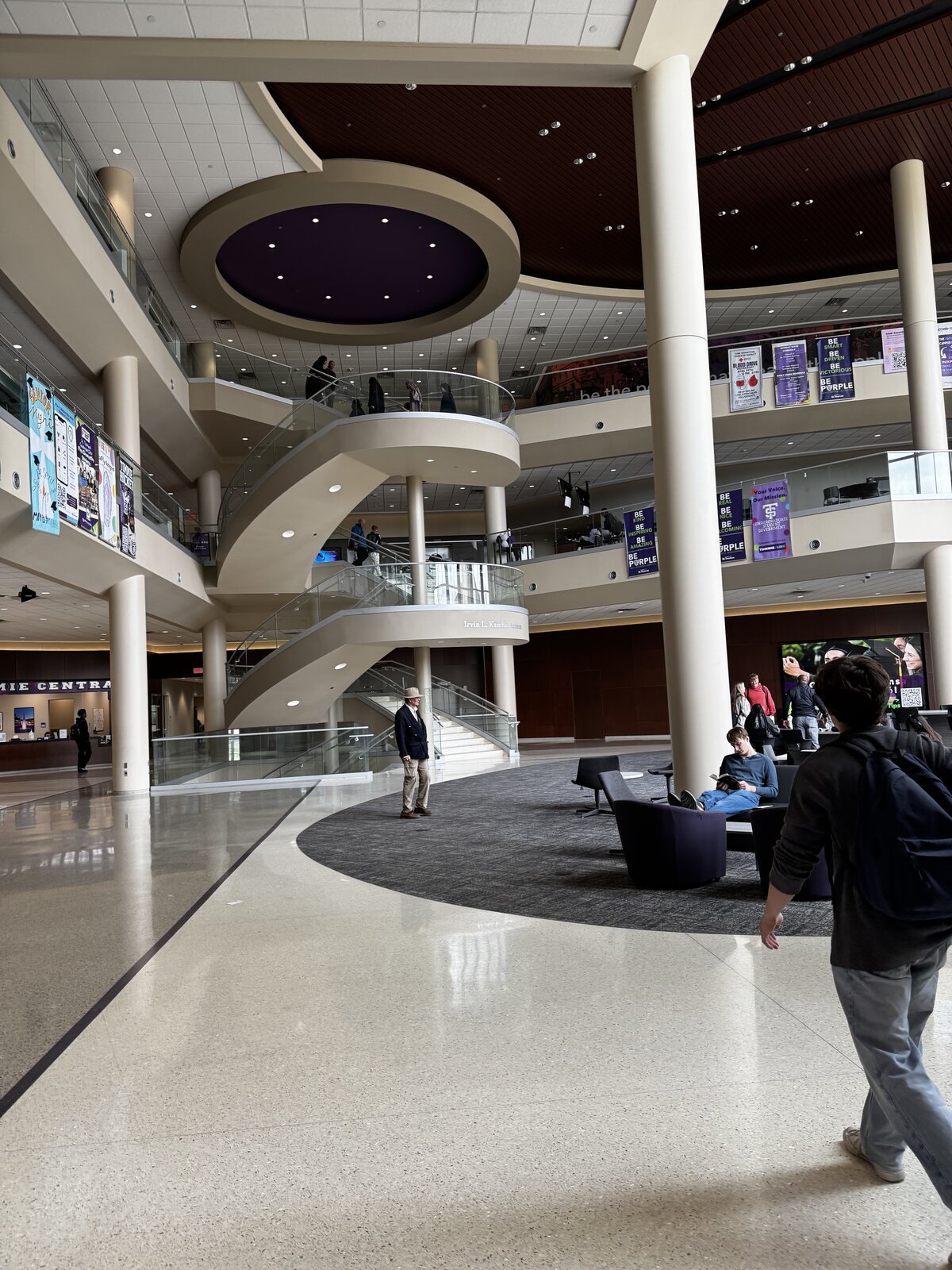 The multi-story Anderson Student Center lobby with a sweeping spiral staircase and purple Tommies banners
