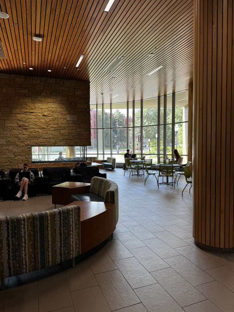 Students studying in a bright lounge with wood ceilings and floor-to-ceiling windows